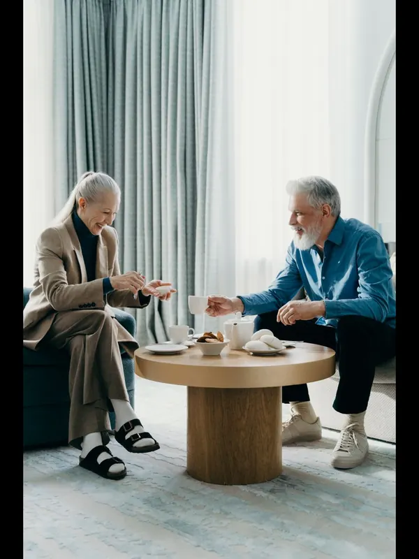 Casal sênior tomando café e sorrindo em casa, representando a aposentadoria