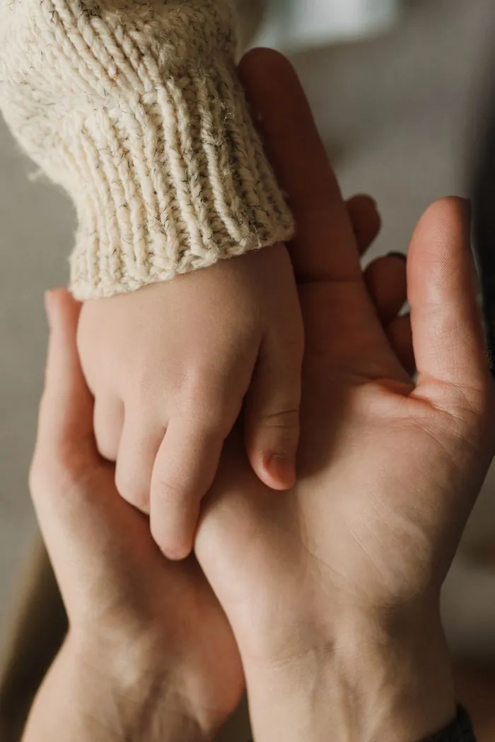 Mãos de adulto e criança entrelaçadas, representando a pensão por morte